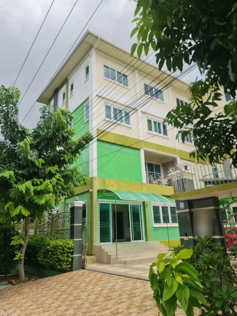 Green and cream 4-storey building with a gated, tiled forecourt