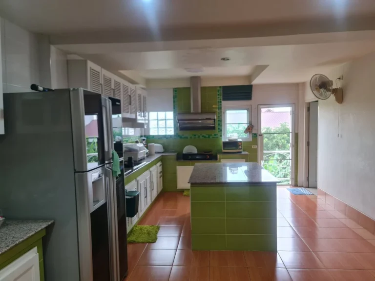 Wide view of the large kitchen, its granite-topped island and the door to the balcony
