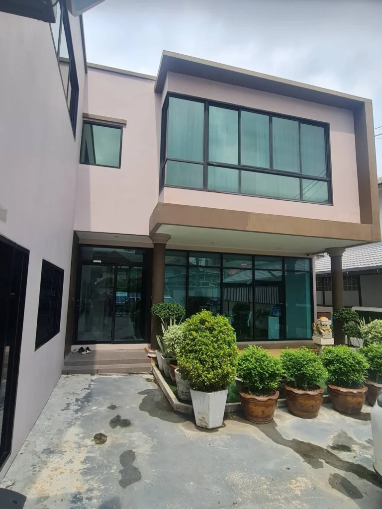 Front of the modern building with its glass façade and potted plants