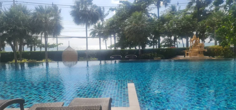 The project’s beachfront pool among palm trees, with the sea at Jomtien beyond
