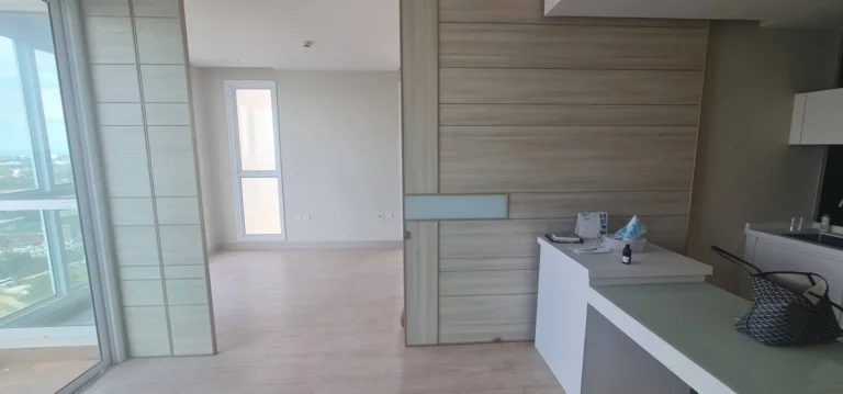 Living area next to the kitchen counter, with wood-look wall panels and a sliding door