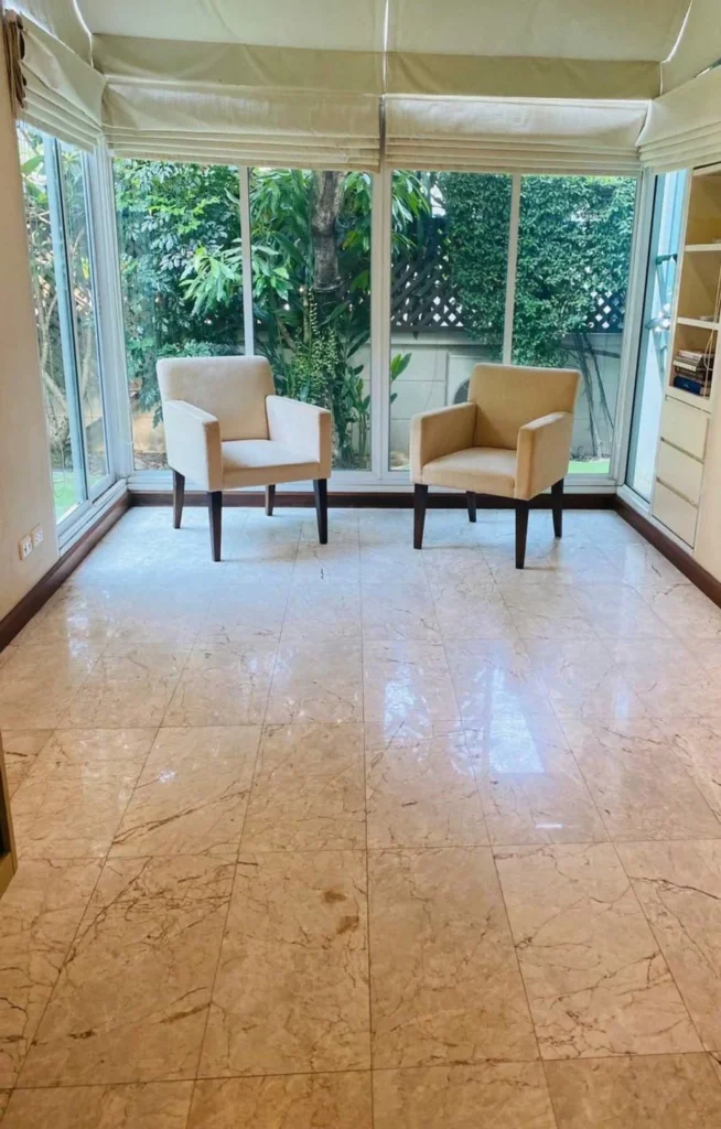 Glass sunroom at the back of the house with a marble floor and a garden view