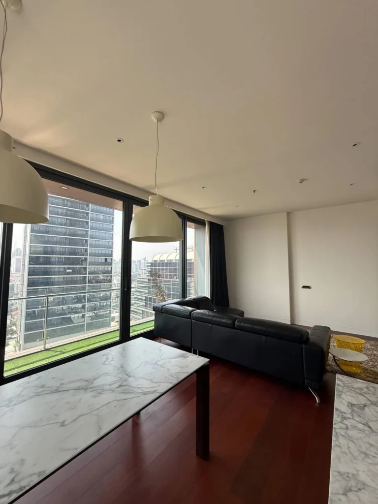 Marble-top dining table by floor-to-ceiling glass, next to the balcony with artificial grass