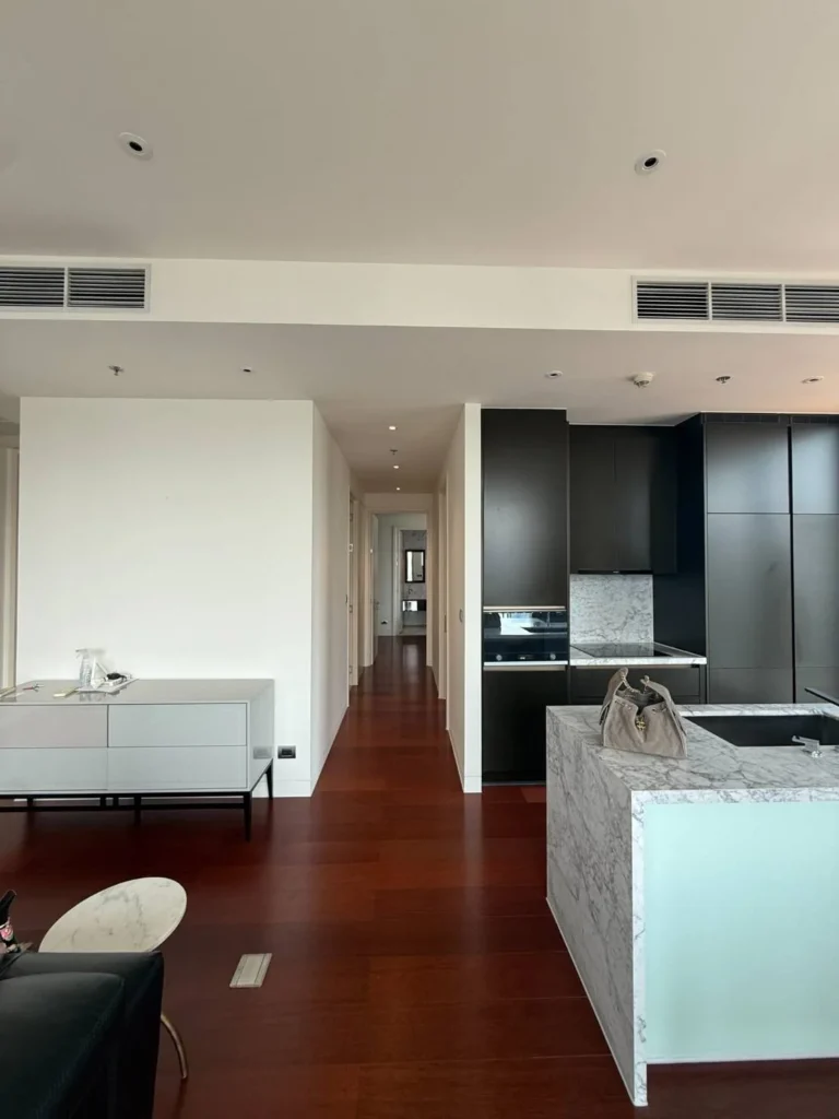Open kitchen with black built-in cabinets, oven, induction hob, marble splashback and marble island