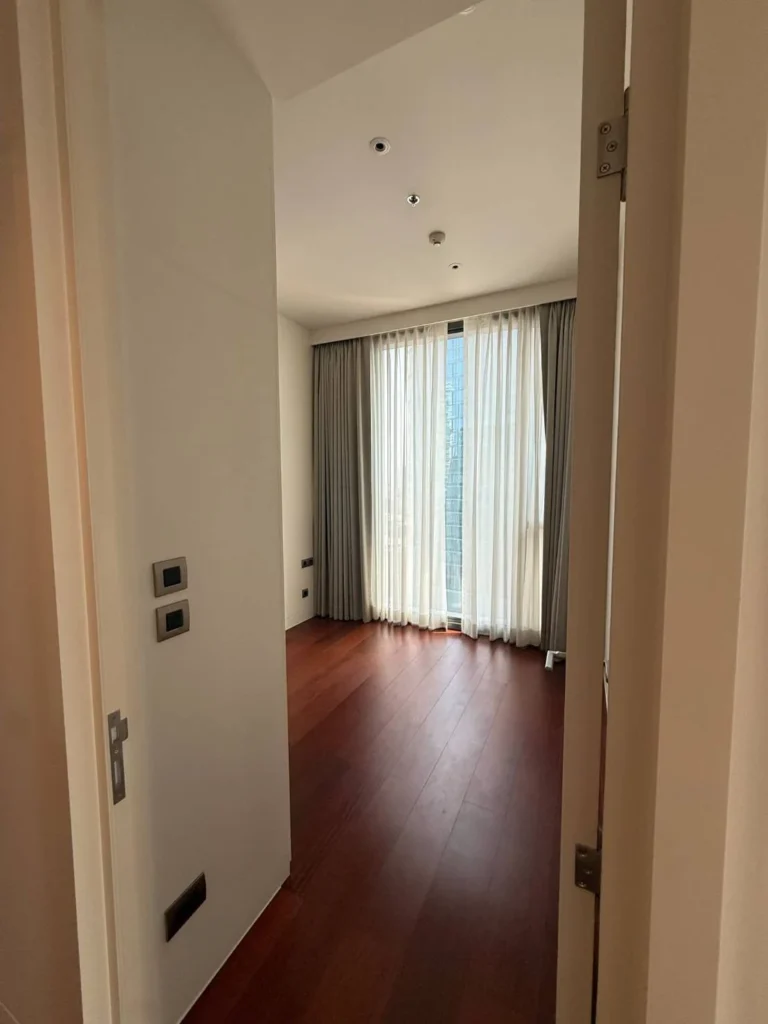 Second bedroom with a wood floor, a tall window and sheer and grey curtains
