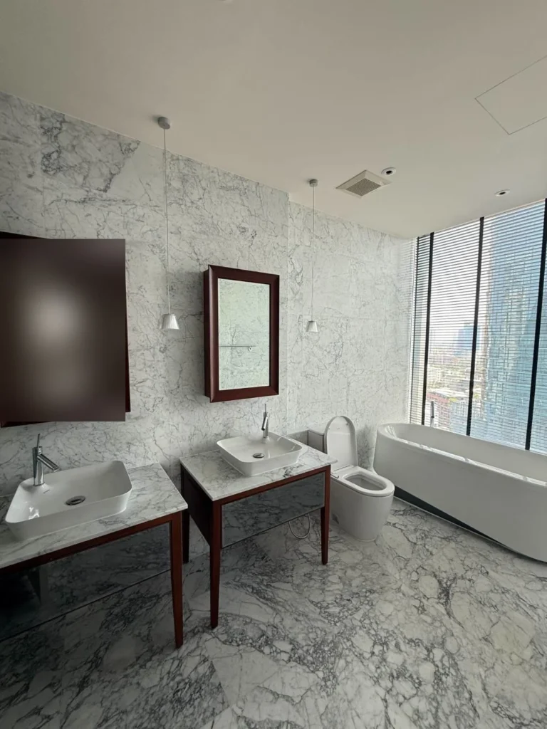 Freestanding bathtub by the window with a city view, beside the double vanity