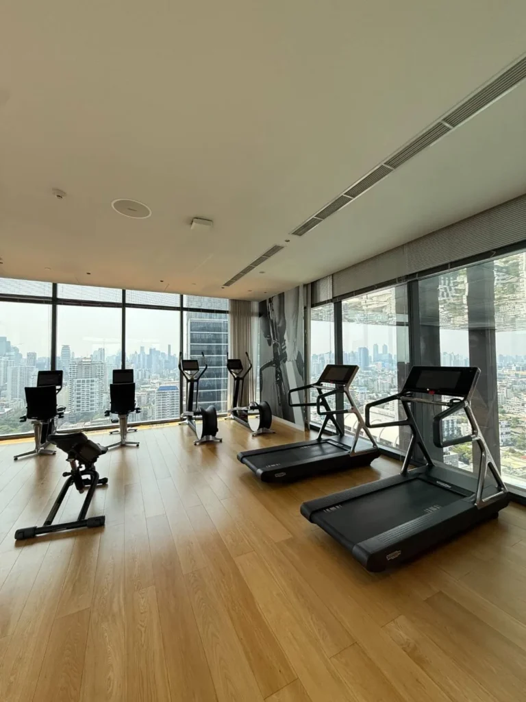 Fitness room with treadmills, cross-trainers and floor-to-ceiling windows onto the city