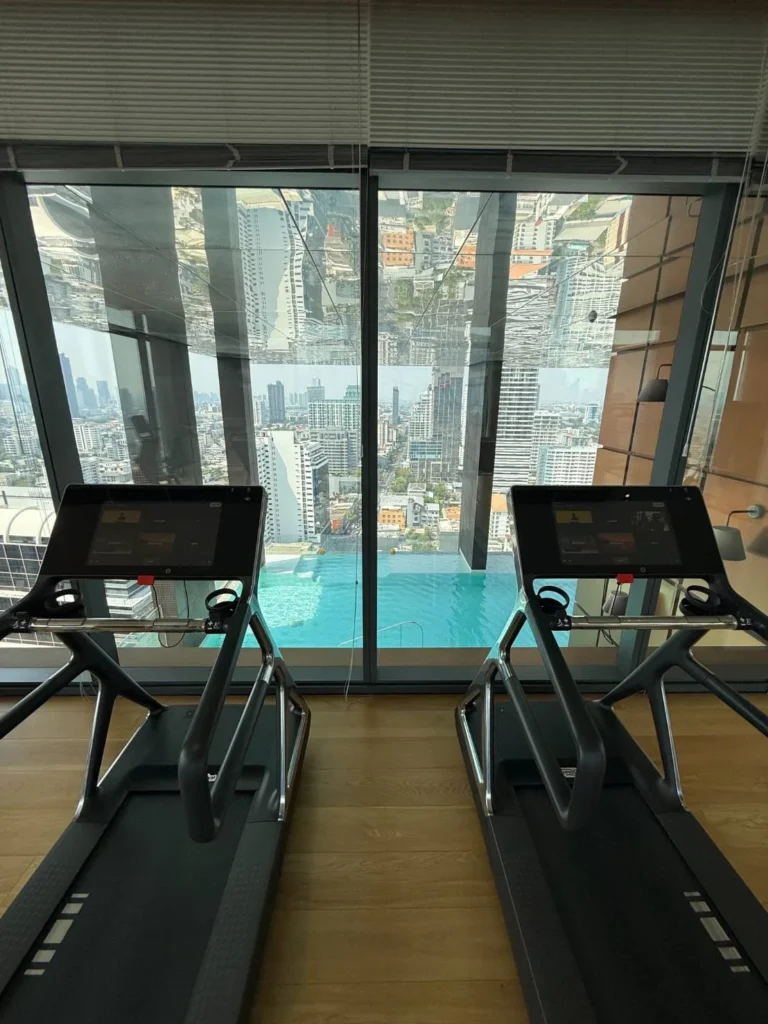 Treadmills facing a glass wall that looks onto the pool