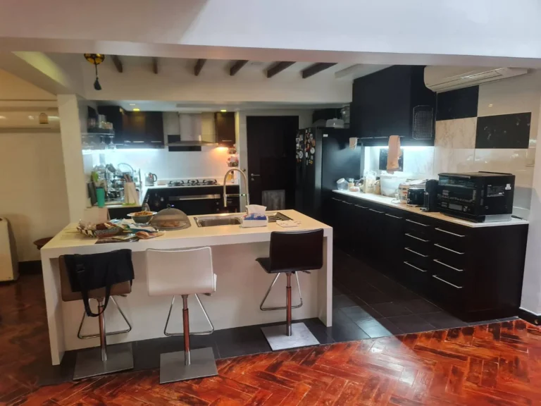 Kitchen with a white island, bar stools and black cabinetry