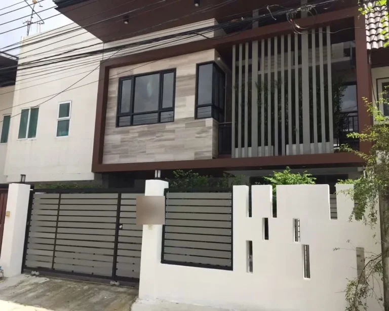 Front of the modern two-storey townhouse with stone-look cladding, vertical slats and a sliding gate