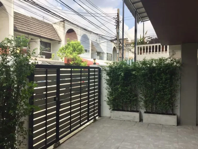 Parking area in front of the house, with a slatted gate and potted bamboo