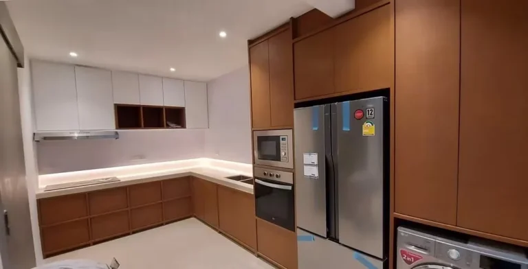 Wide view of the kitchen with tall wood-tone cabinets, a French-door fridge and a built-in oven and microwave