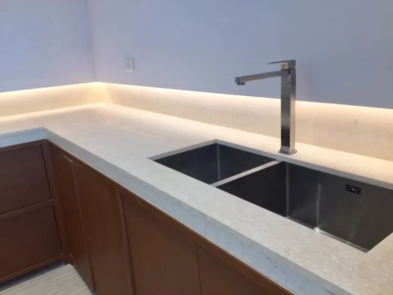 Stainless steel double sink with a stone worktop and under-cabinet lighting
