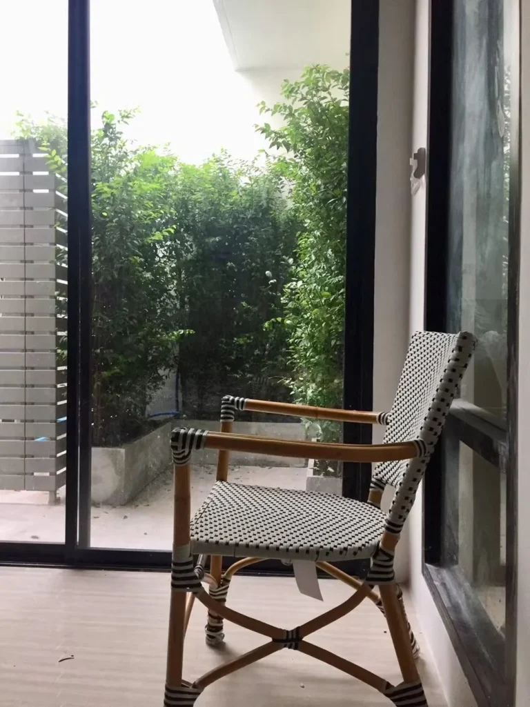 Rattan chair by the glass door, looking out to the private garden