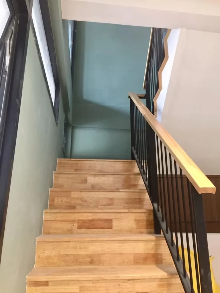 Wooden staircase with a black steel railing and sage-green walls