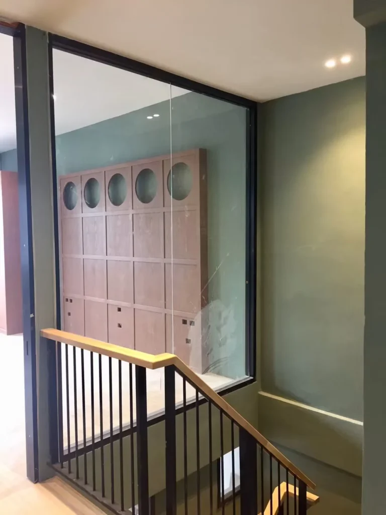 Glass wall at the upstairs landing, with the wooden wall with circular niches beyond