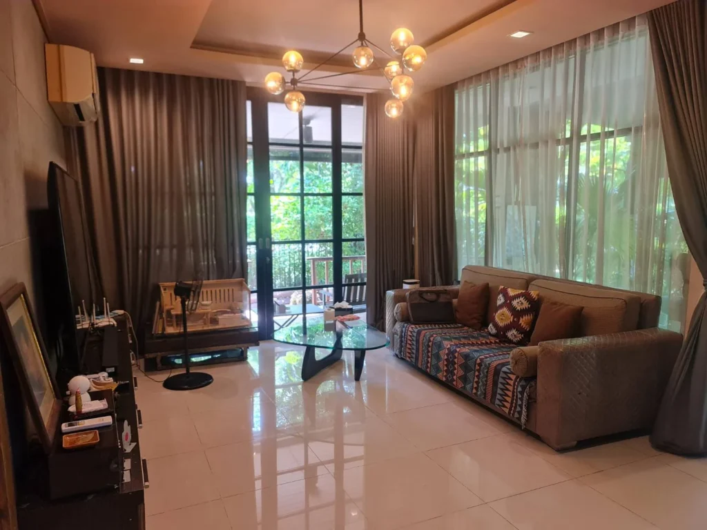 Living room with a chandelier and tall glass walls facing the garden