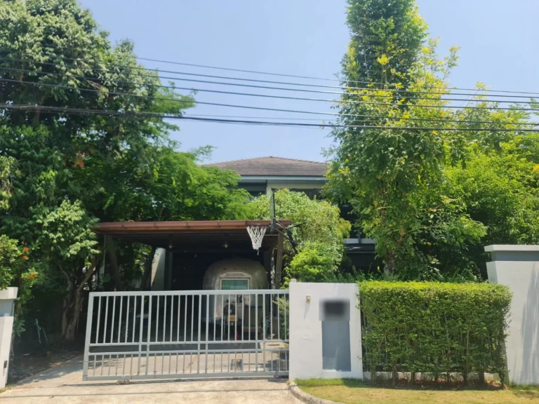 Front of the house behind mature trees, with the covered carport
