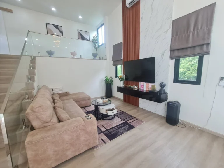 Double-height living room with marble TV wall and glass-railed mezzanine