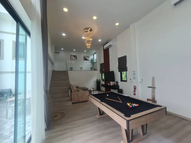 Pool table under a crystal chandelier, stairs to the mezzanine