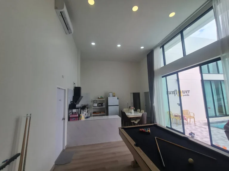 Pool table and kitchen, glass doors open to the pool